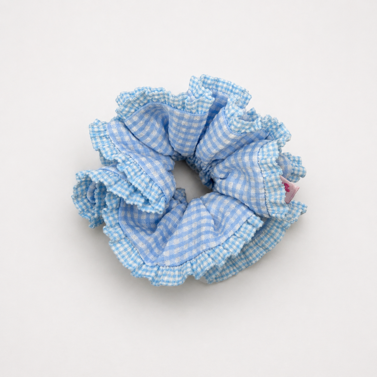 Productfoto van een lichtblauwe scrunchie met ruitjes op een witte achtergrond