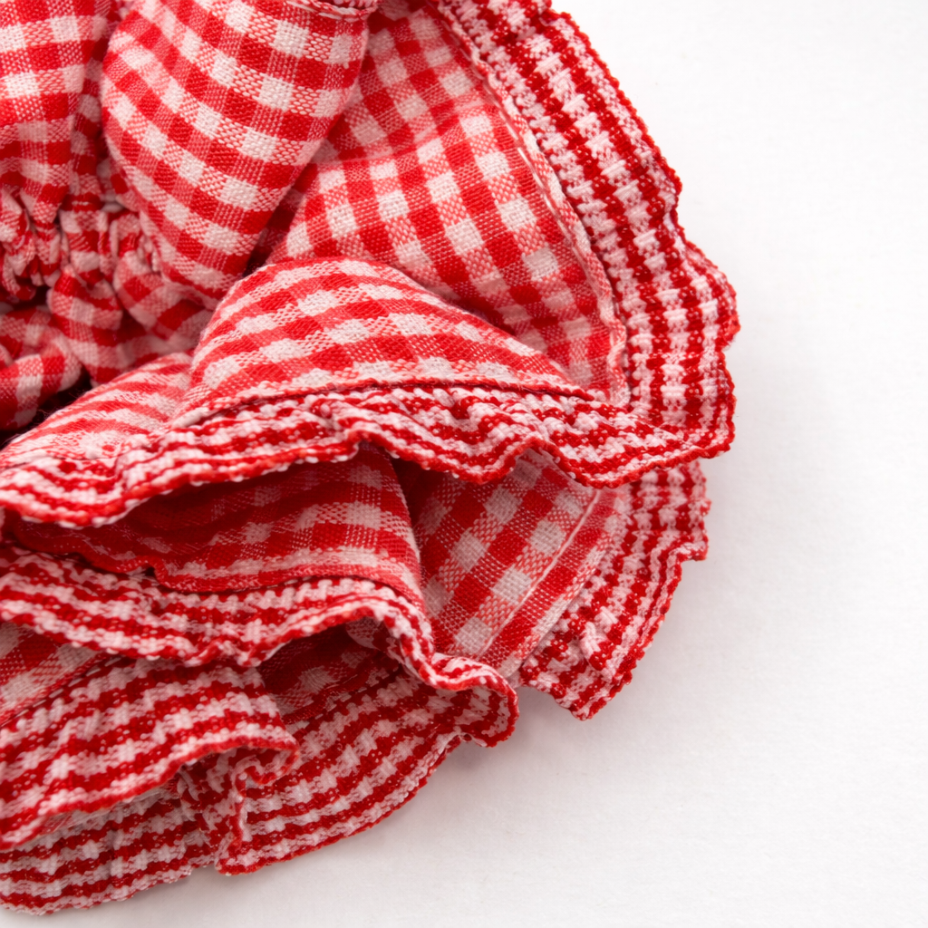 Detailfoto van rode scrunchie met ruitjes op witte achtergrond