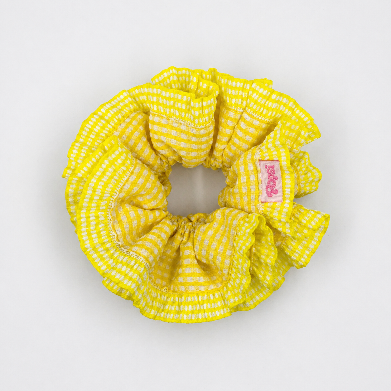 Productfoto van een gele scrunchie met ruitjes op een witte achtergrond