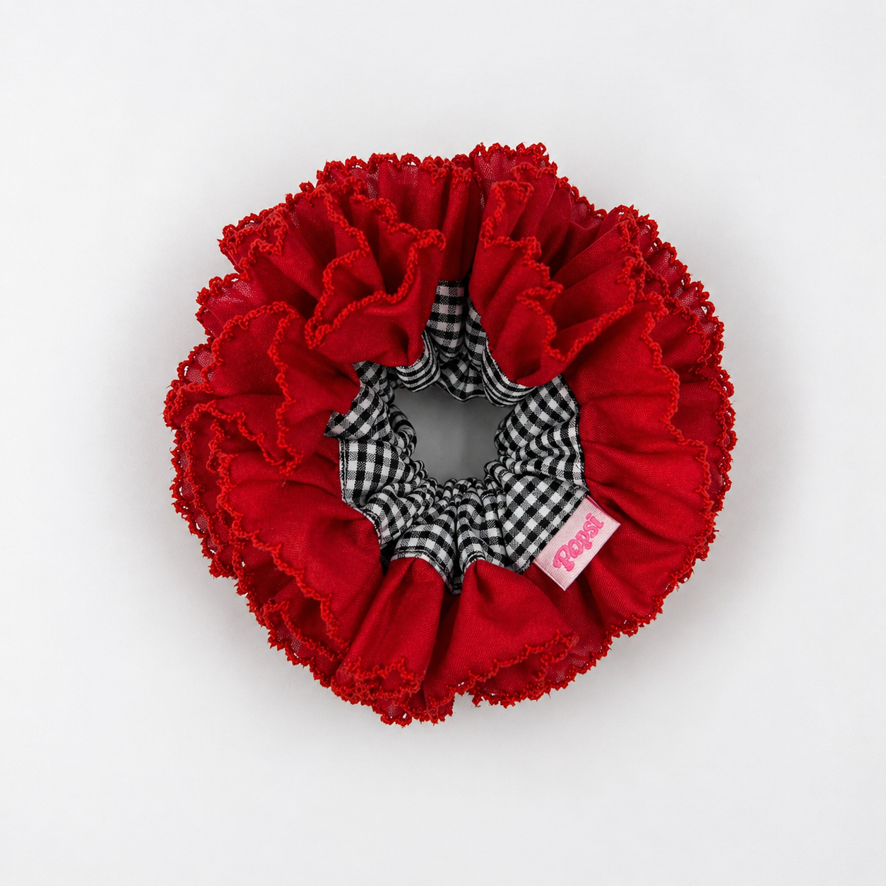Productfoto van een rode scrunchie met zwart witte ruitjes op een witte achtergrond