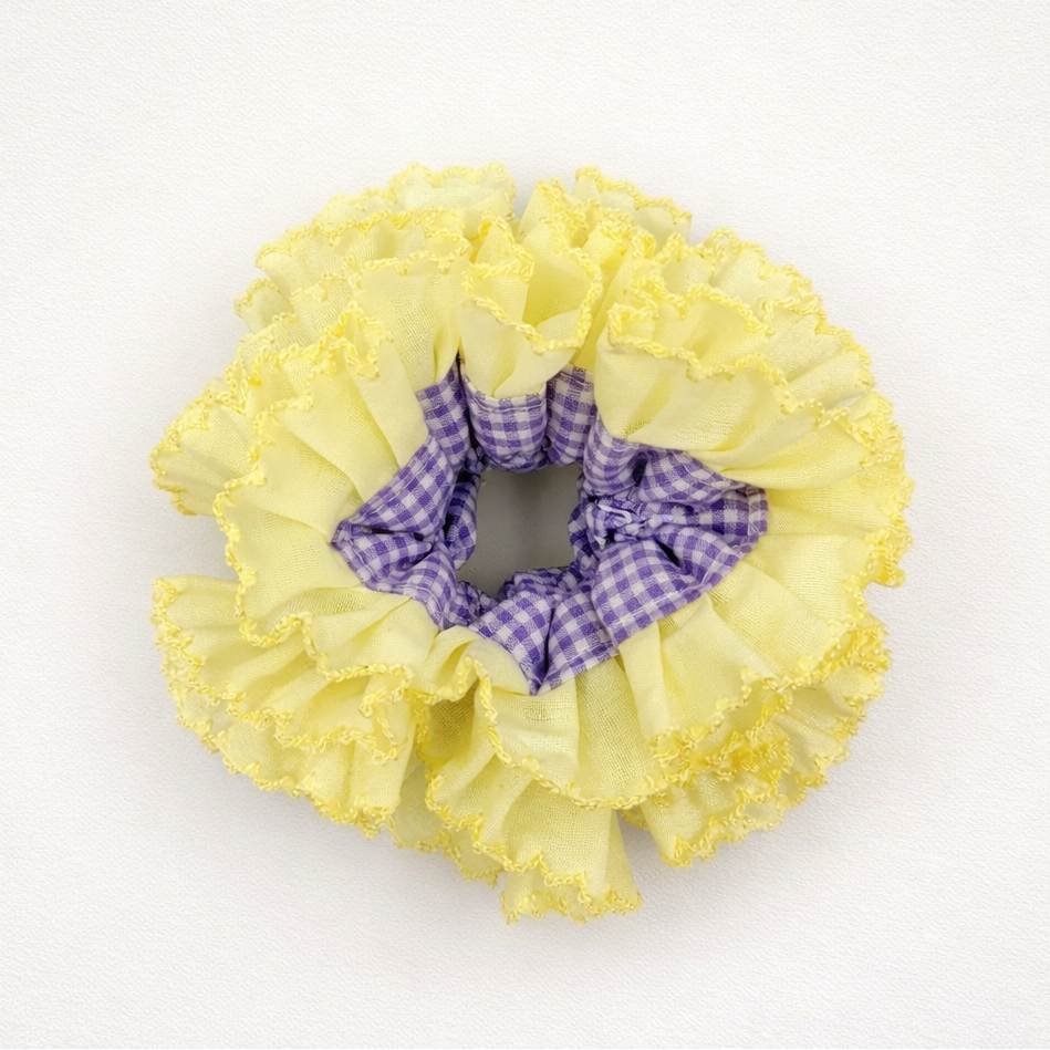 Productfoto van een gele scrunchie met paarse ruitjes op een witte achtergrond
