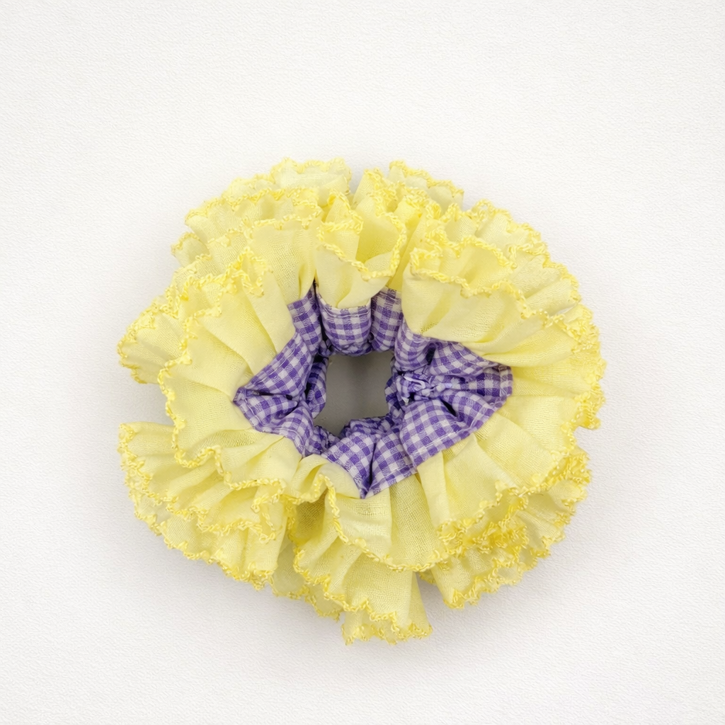 Productfoto van een gele scrunchie met paarse ruitjes op een witte achtergrond
