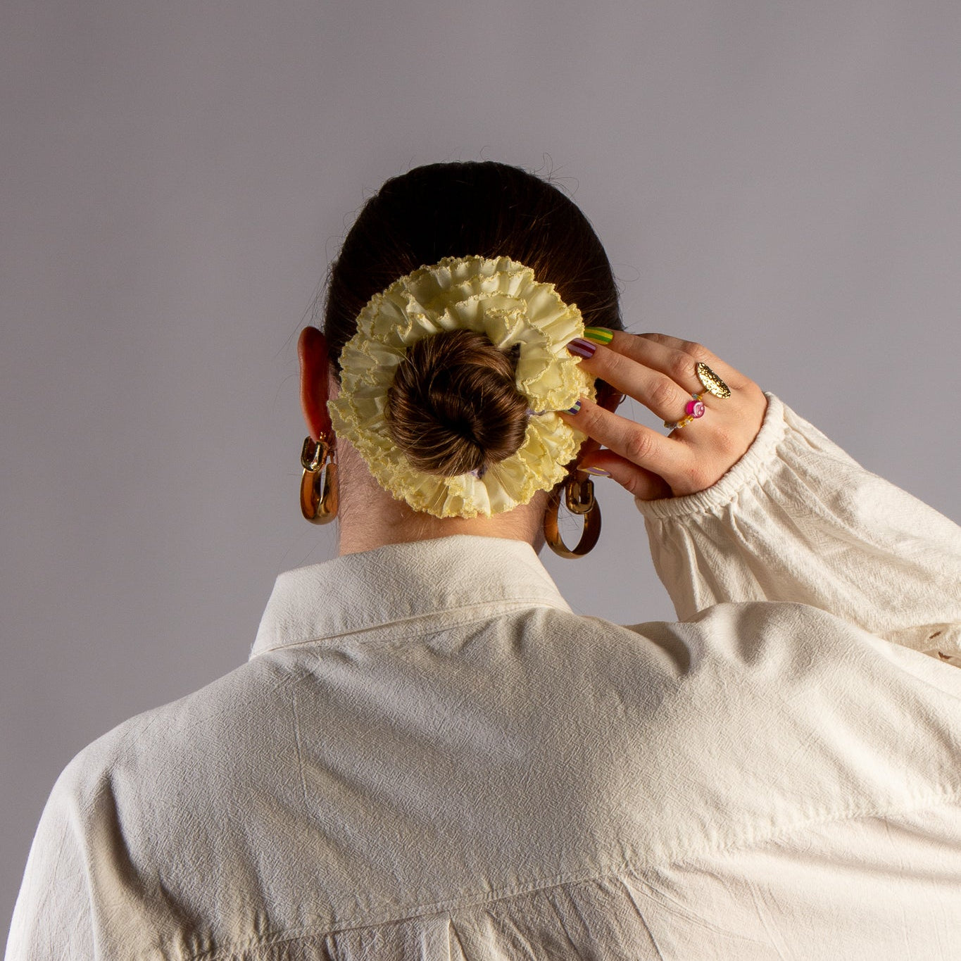 Model foto met gele scrunchie in haar met witte blouse in studio