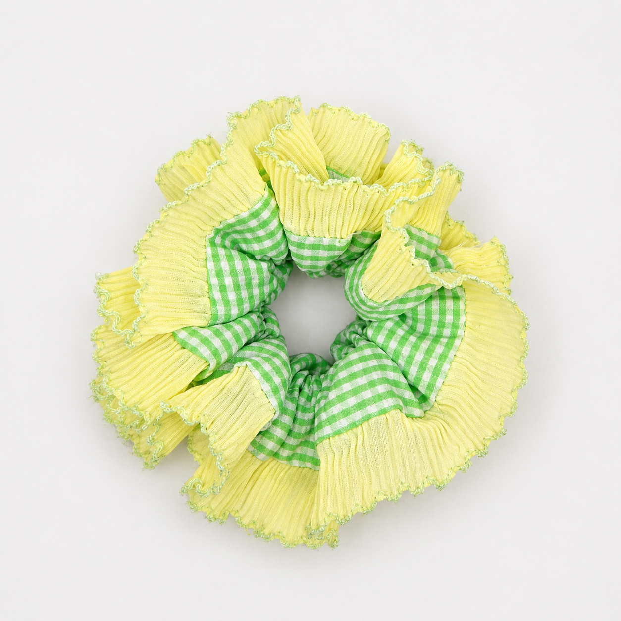 Productfoto van een geel met groene scrunchie op een witte achtergrond