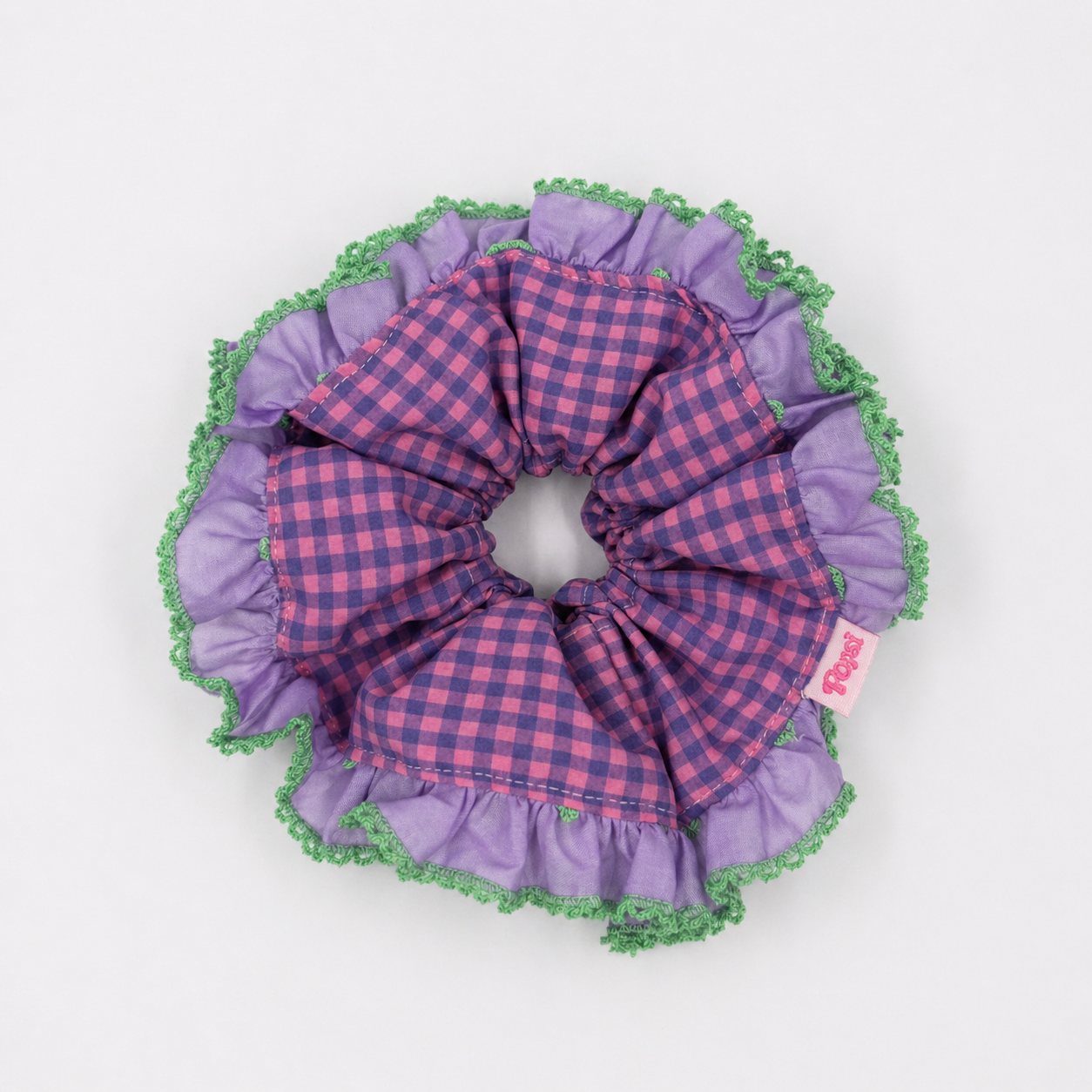 Productfoto van een paars met groene scrunchie met ruitjes op een witte achtergrond