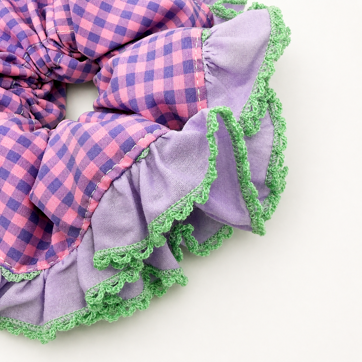 Detail foto van een paars met groene scrunchie met ruitjes op een witte achtergrond