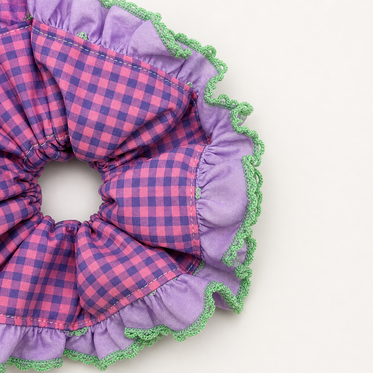 Detail foto van een paars met groene scrunchie met ruitjes op een witte achtergrond