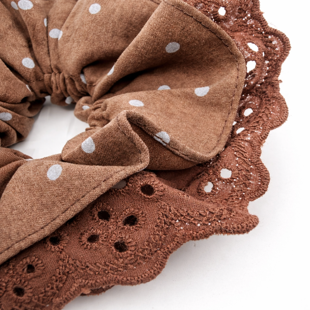 Detailfoto van bruine scrunchie met stippen op witte achtergrond