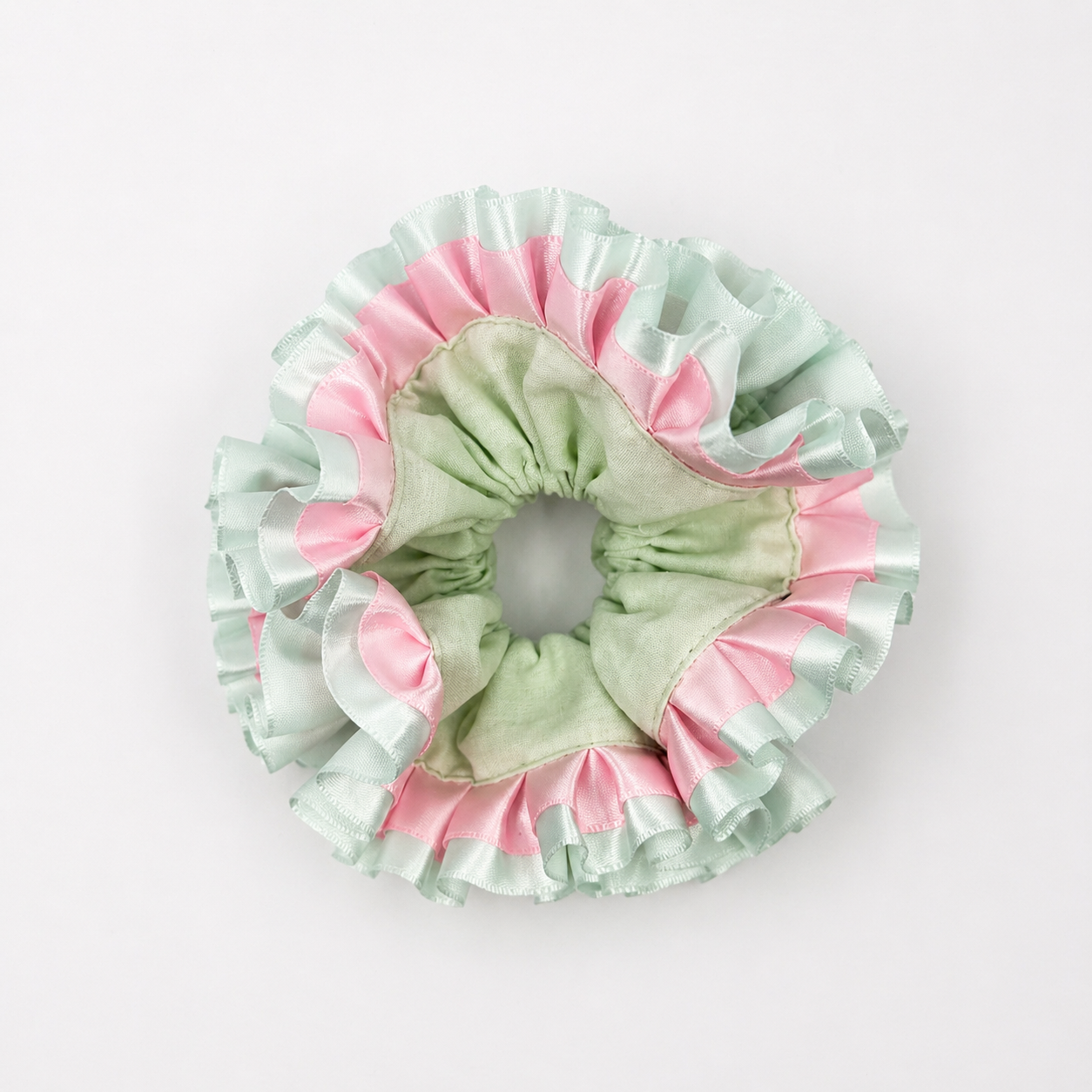 Productfoto van een mintgroene scrunchie met roze op een witte achtergrond