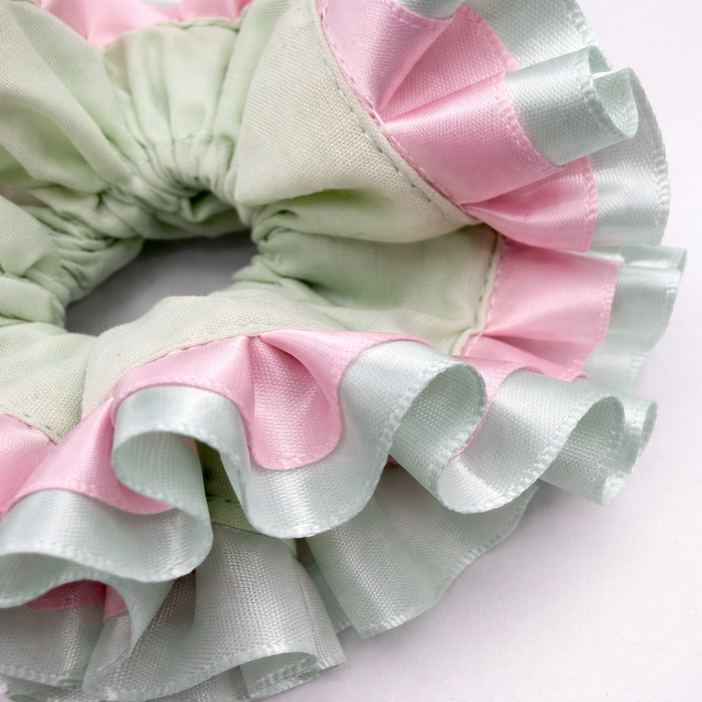 Detailfoto van mintgroene scrunchie met roze op witte achtergrond