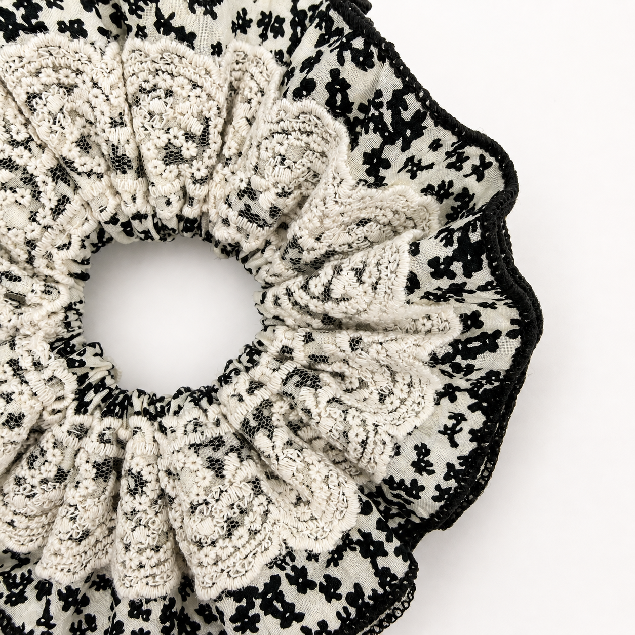 Detail foto van een zwart wit kanten scrunchie op een witte achtergrond