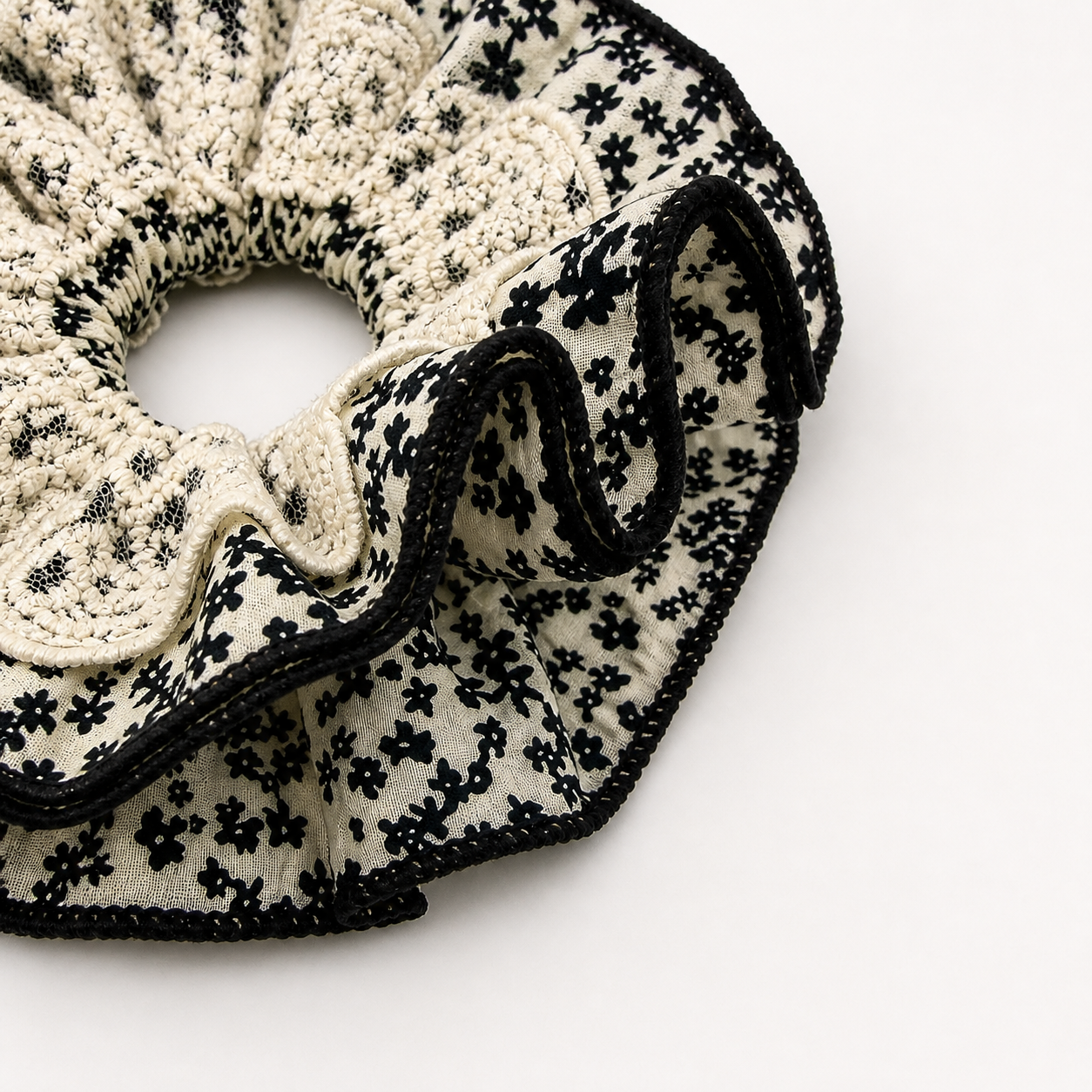 Detail foto van een zwart wit kanten scrunchie op een witte achtergrond